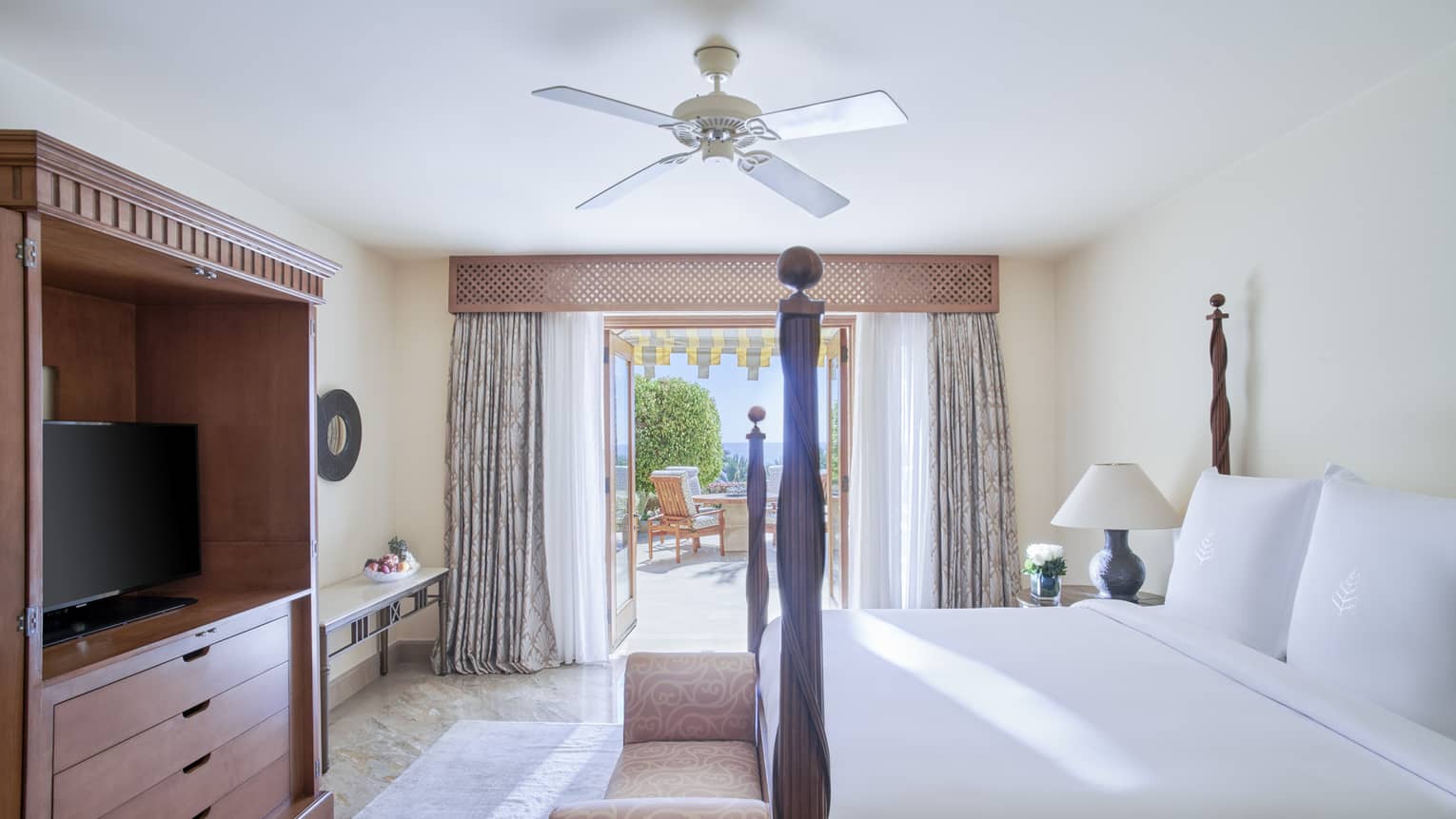 Bedroom with four-poster king bed, dresser, TV and walk-out terrace