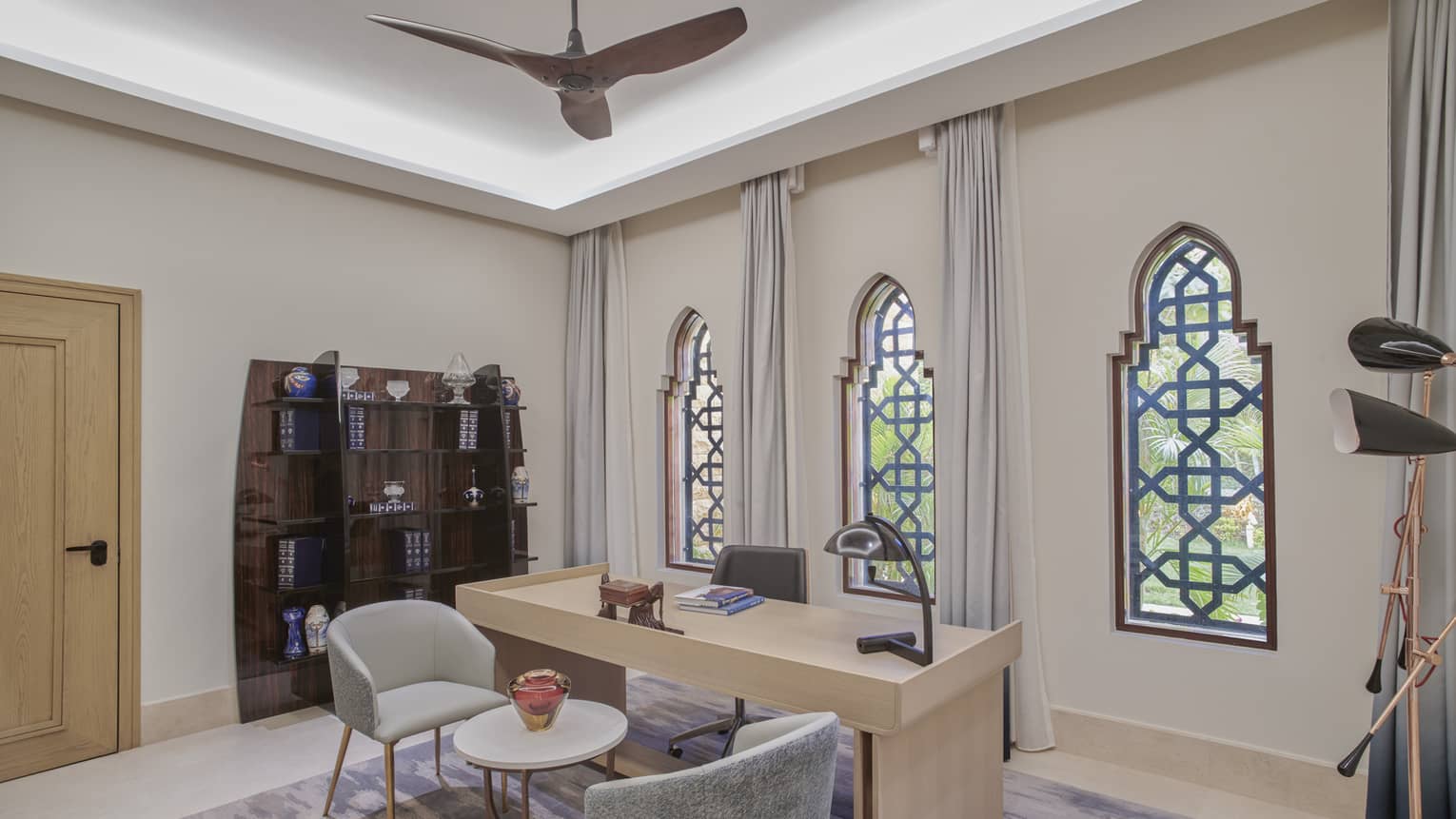 Office with desk, small table and two chairs and three ornate windows