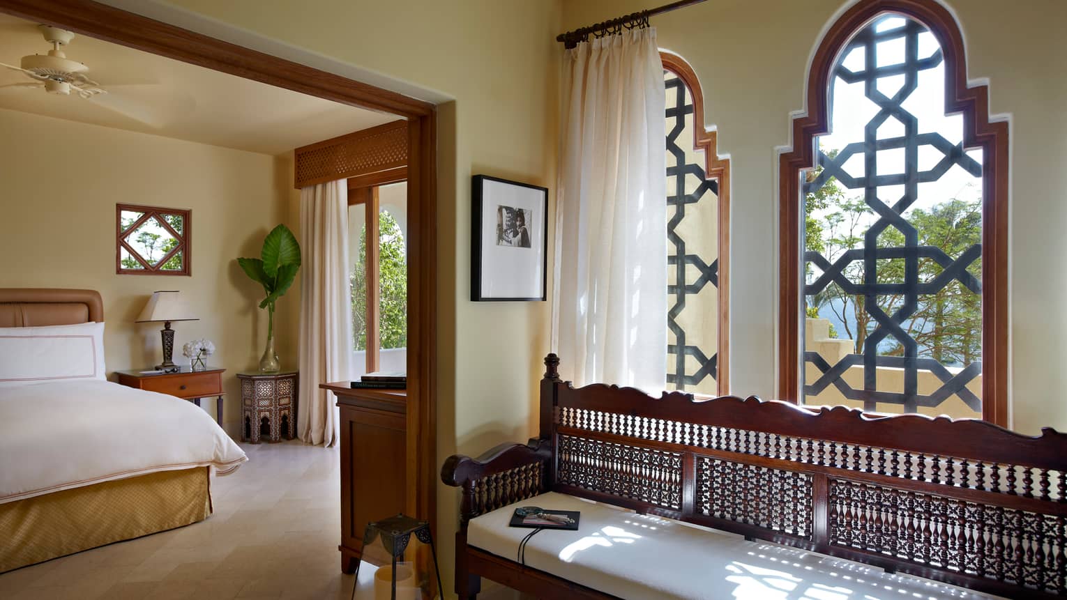 Four Bedroom Villa sunny bedroom with bed, nightstand, balcony door, long decorative wood bench with white cushion