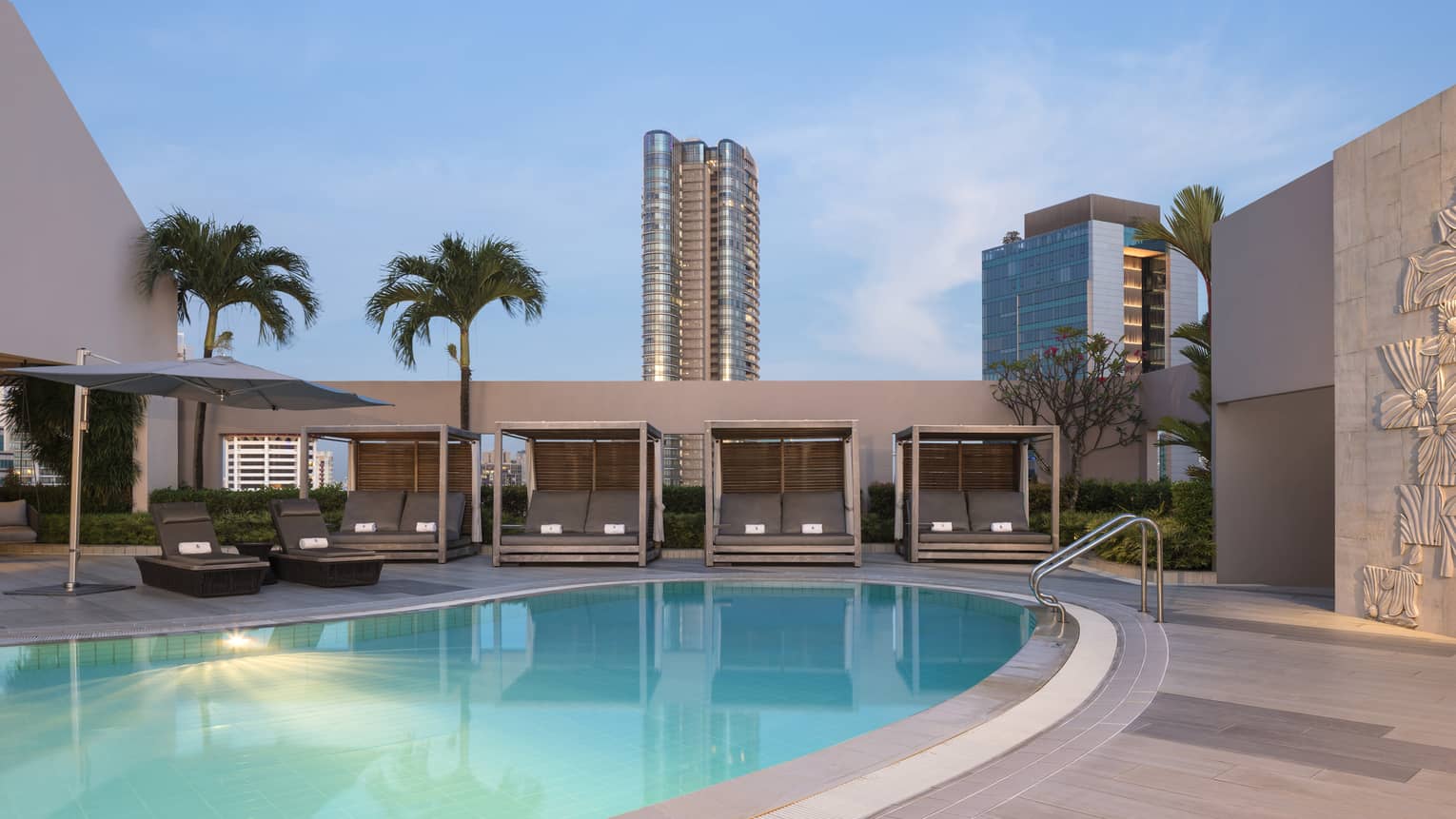 FS Singapore Family Pool at dusk, views of palm trees and skyscrapers