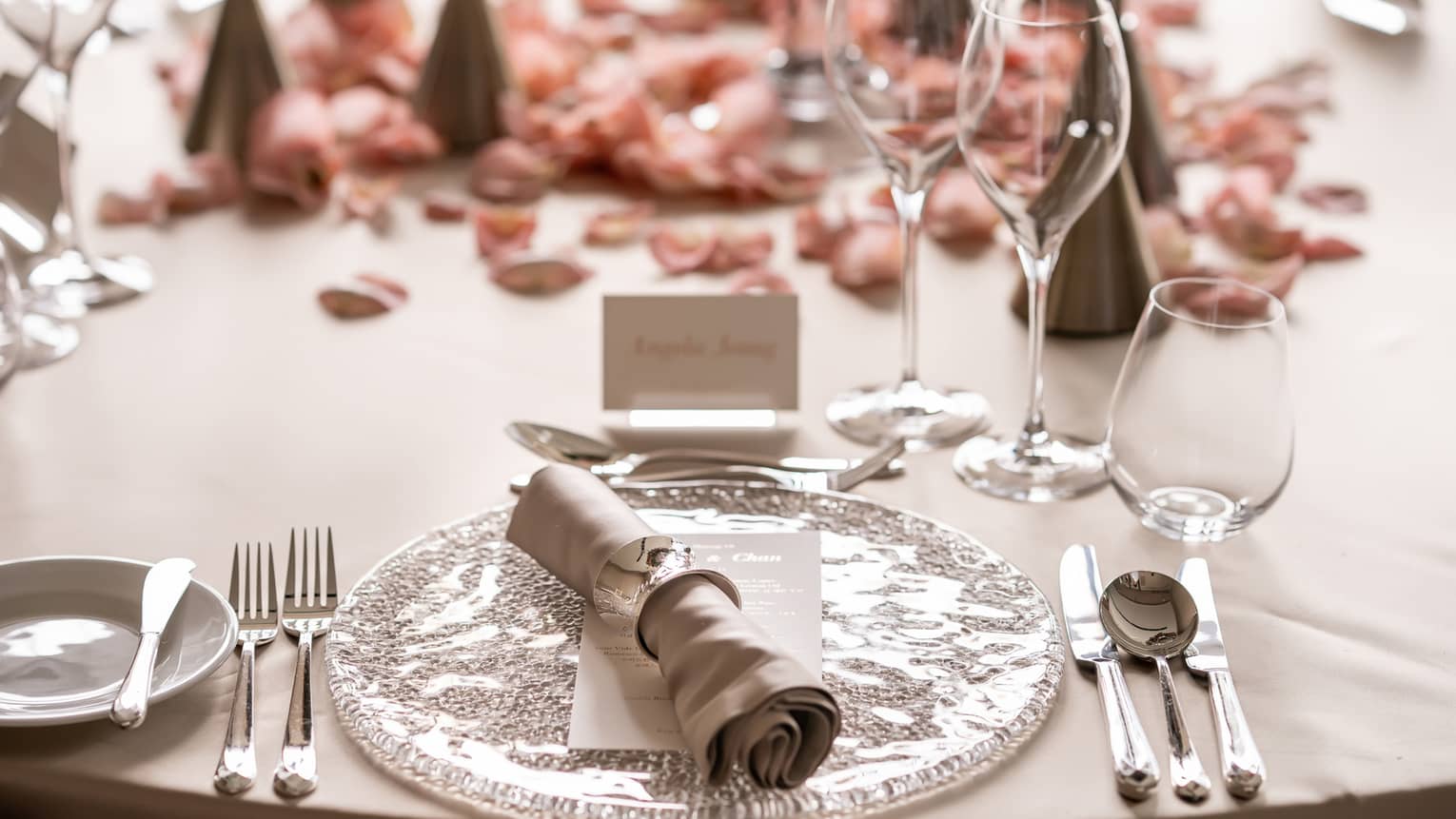 Wedding place setting with name card and pink rose petals