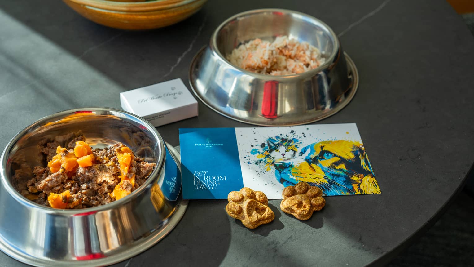 Dog food bowls and treats with an in-room dining menu beside it.