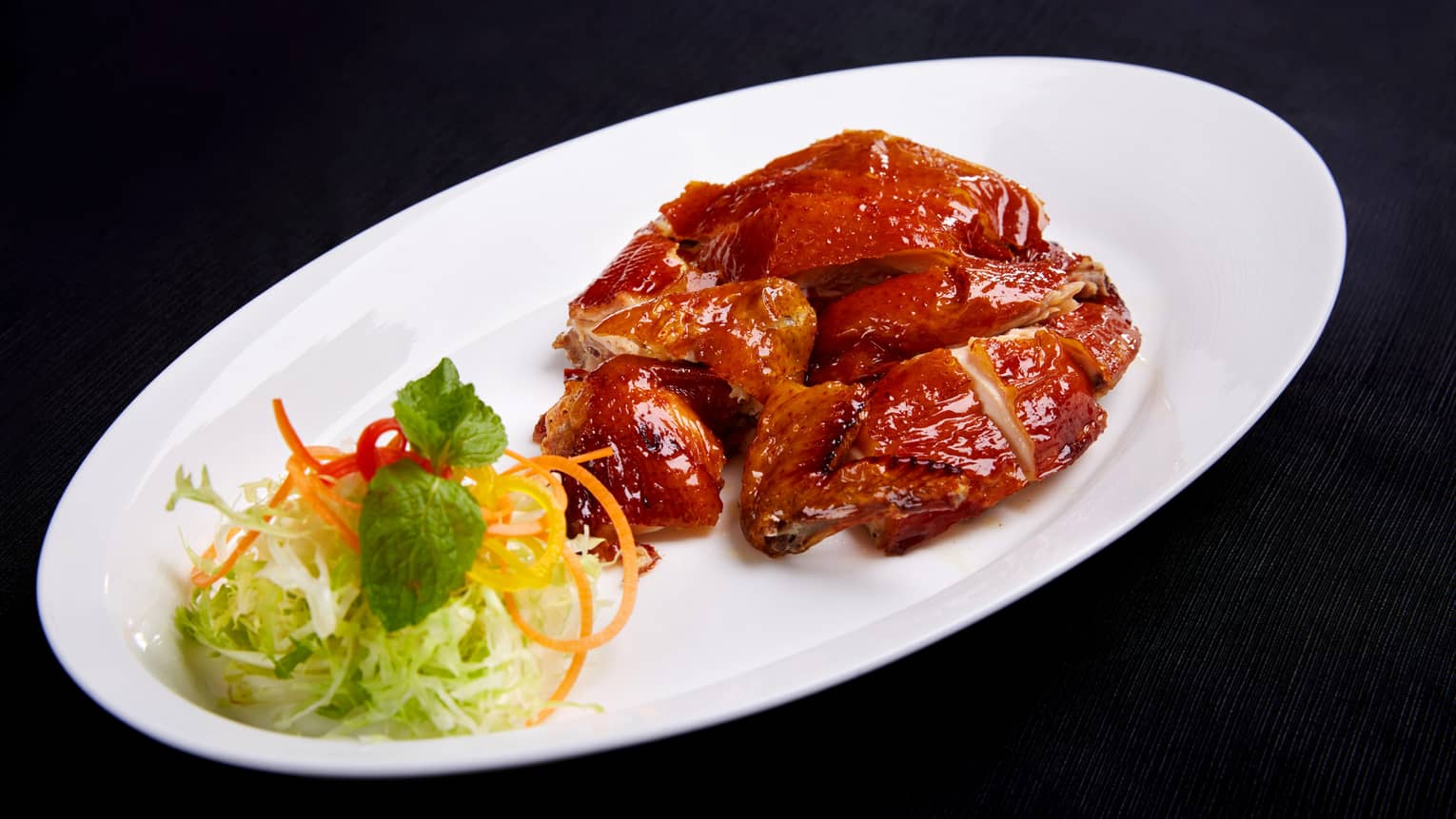 Peking duck on plate with lettuce, carrots, herbs