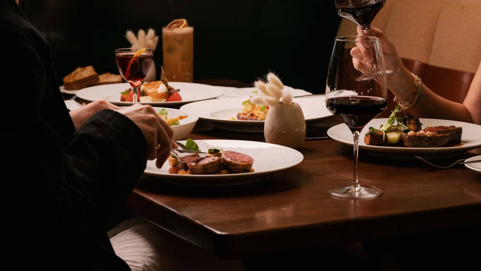 People dine at restaurant table over steak and red wine