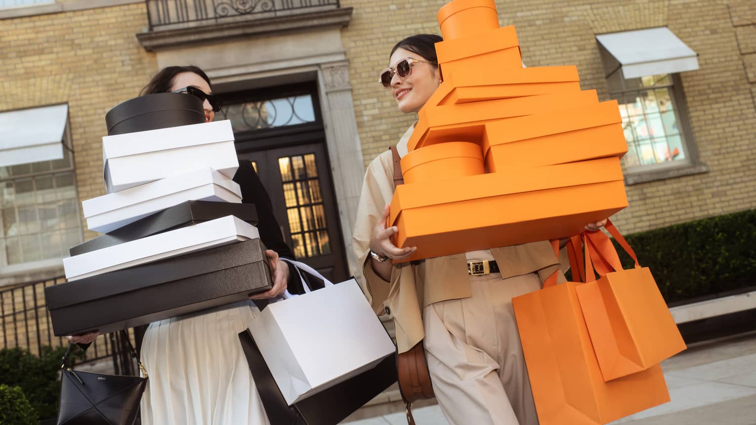 Two women carry many shopping bags and boxes
