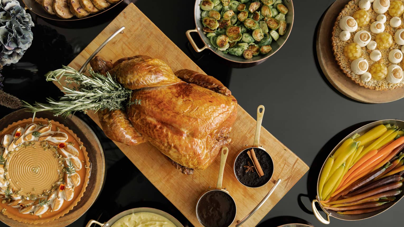 Table set with a roasted turkey, Brussels sprouts, sliced carrots and various other dishes for a holiday meal,Table set with a roasted turkey, Brussels sprouts, clived carrots and various other dishes for a holiday meal
