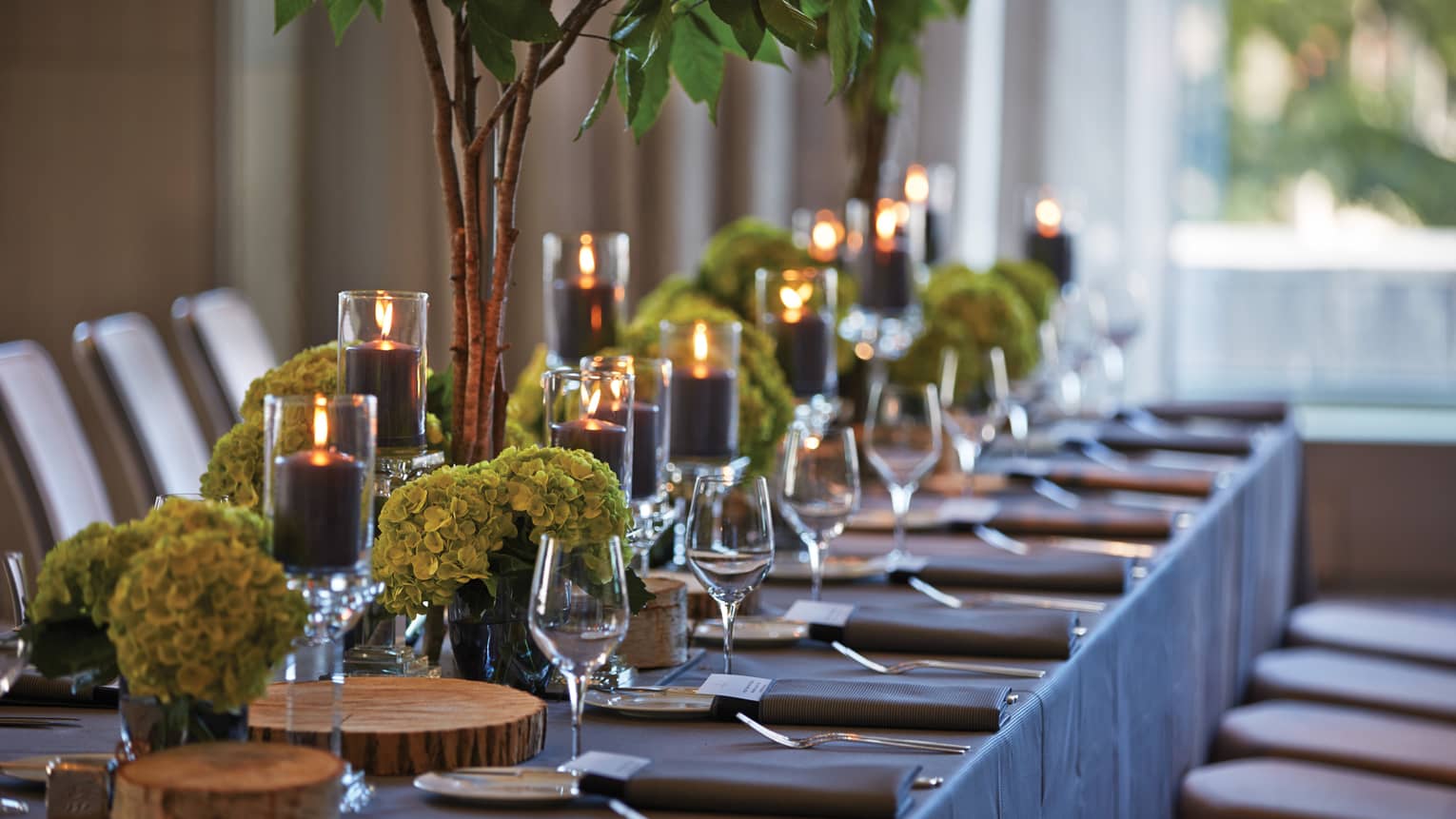 Black pillar candles in votives, green flowers, wine glasses along banquet table