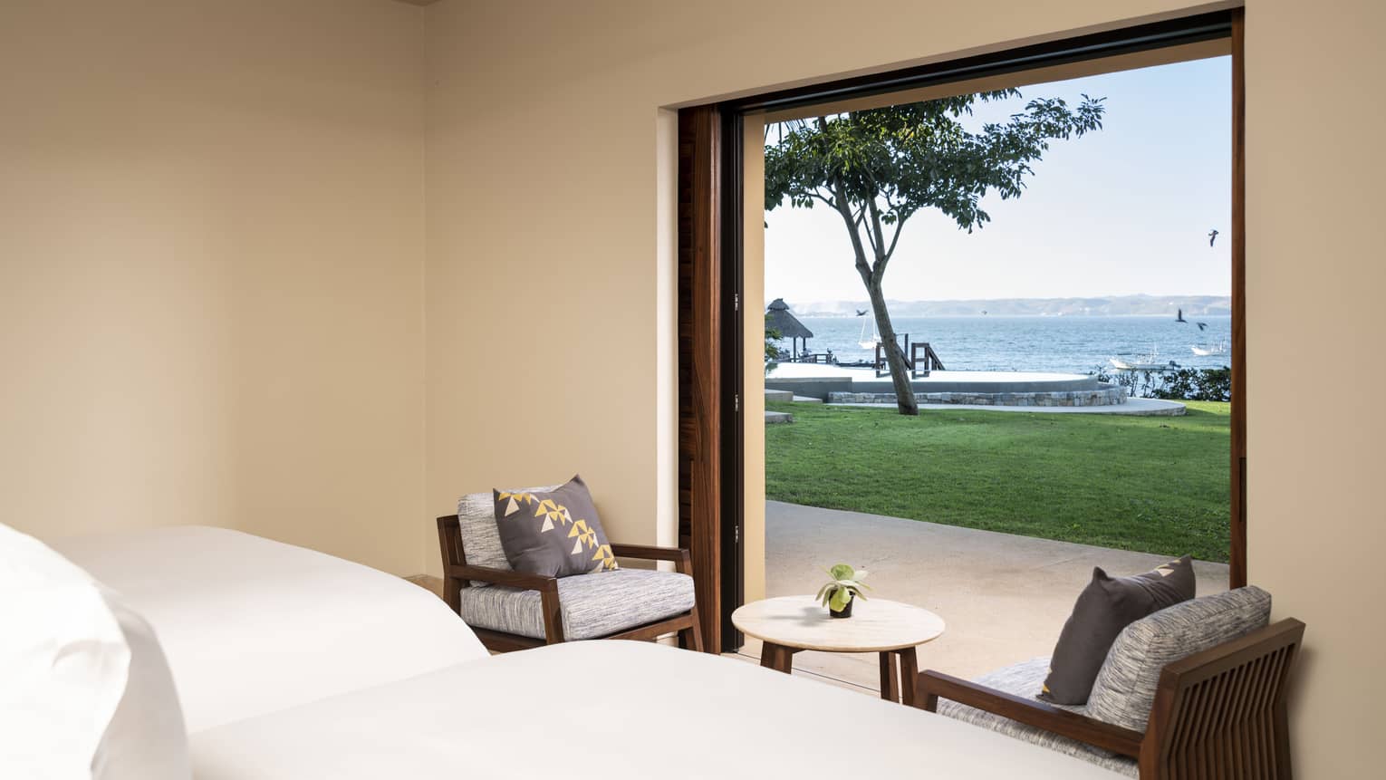 Bedroom with two queen beds looking out to private lawn and the ocean, at Four Seasons Resort Tamarindo