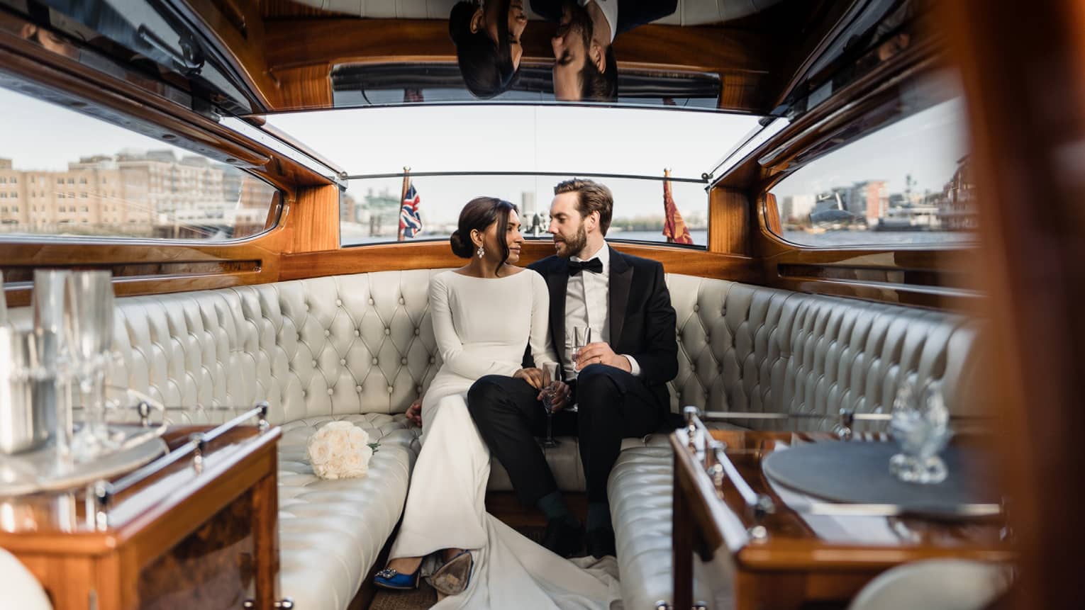 Bridal couple sitting on tufted leather bench on luxury private boat