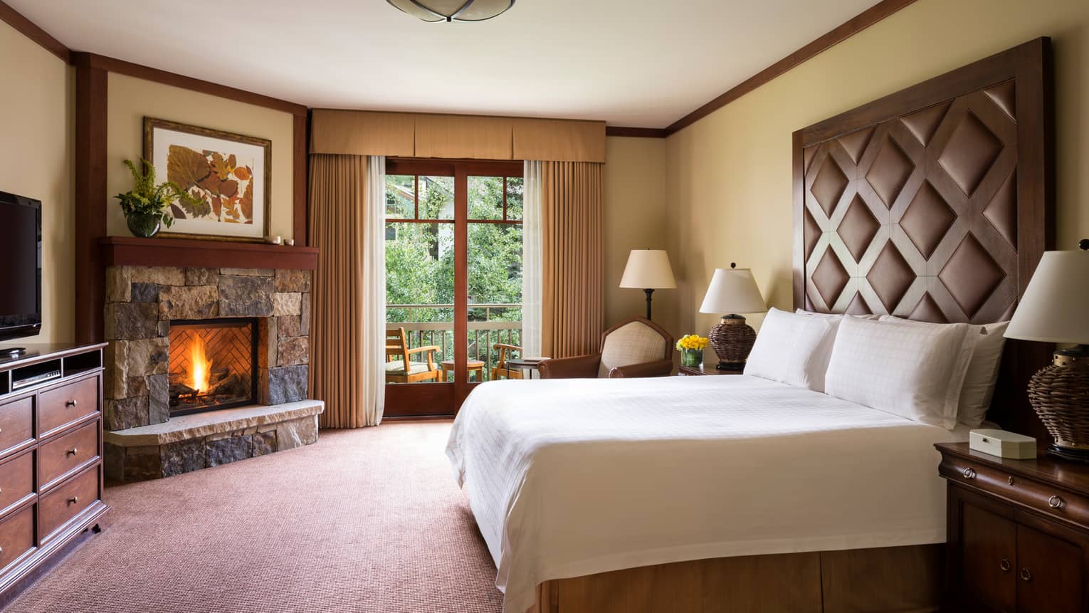 Village View Room bed, gas-burning stone fireplace, balcony with two patio chairs