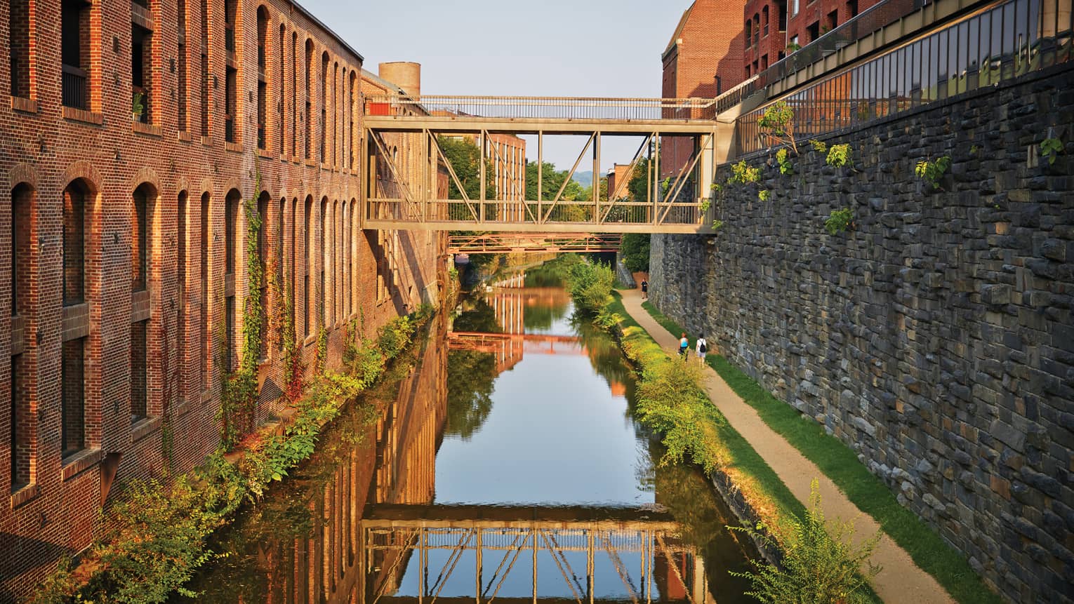 A canal between a stone wall and brick building.