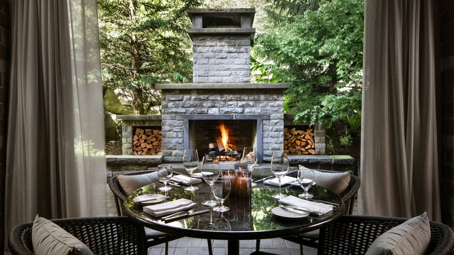 Chairs and tables outside near a stone fireplace.