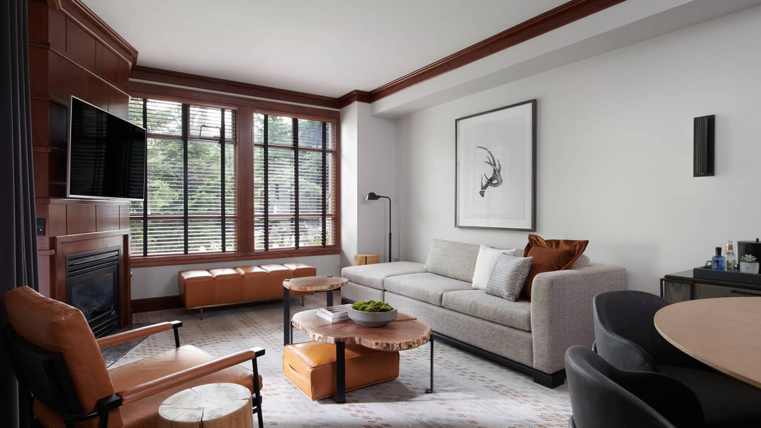 Living room with three-seat grey sofa, leather armchair, TV, wooden coffee tables