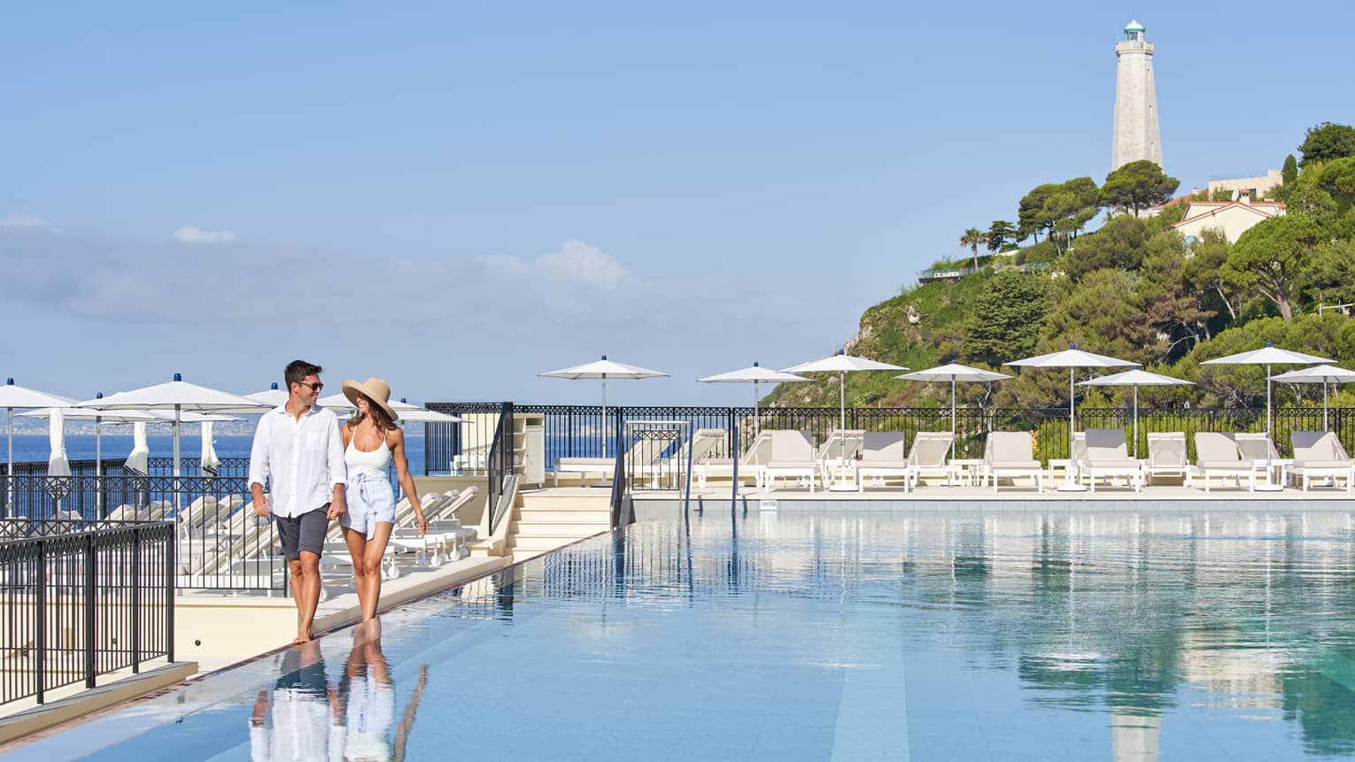 Couple walks along outdoor swimming pool deck at Club Dauphin