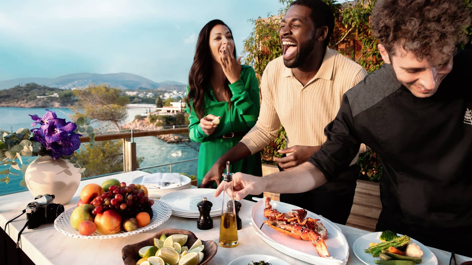 Couple enjoying food prepared by chef outside with view of water.