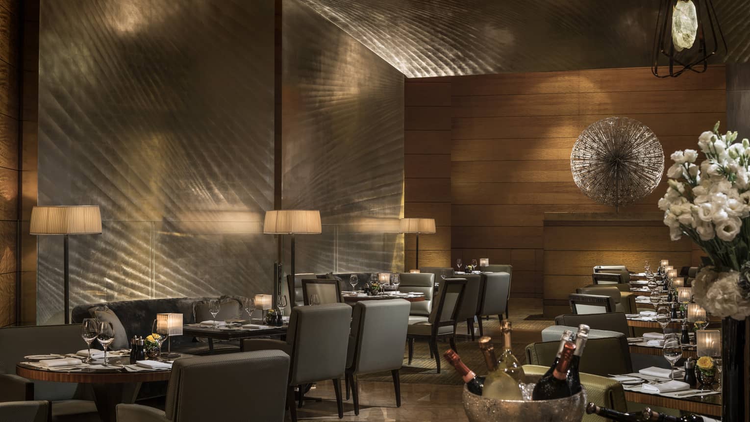Elegant restaurant dining area with softly lit tables, upholstered chairs, and ambient lighting, set for a formal dinner service.