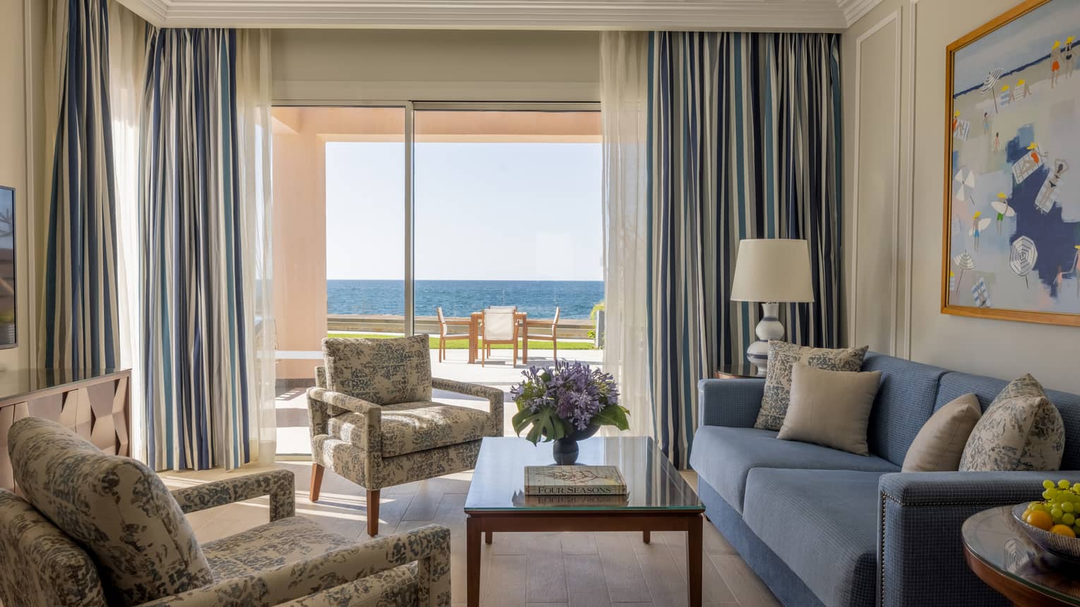 One-Bedroom Beach villa living area with twin patterned armchairs, blue sofa, sliding glass door to terrace