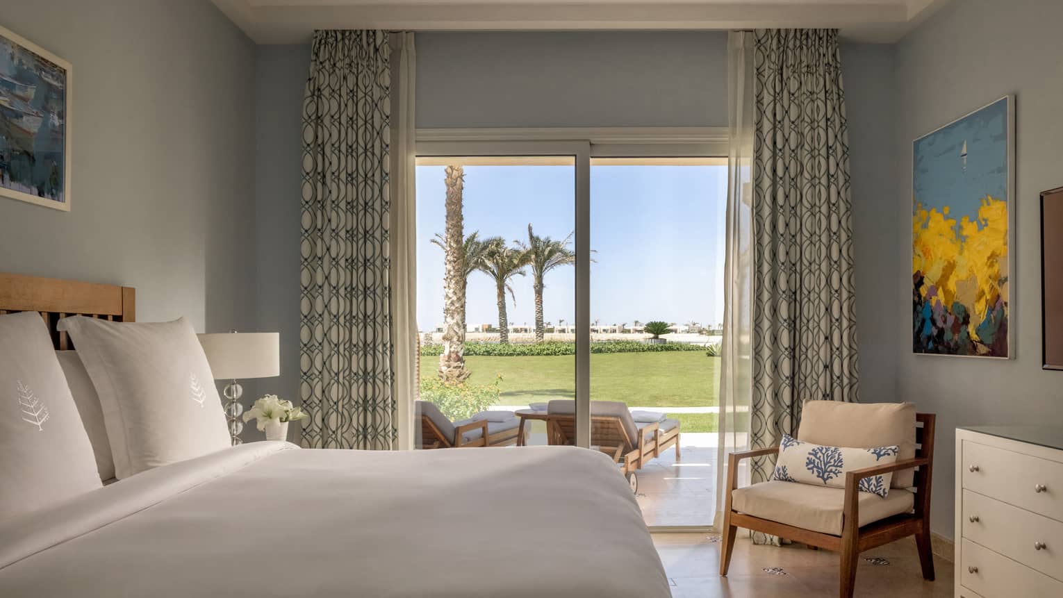 Guest bedroom with king bed, armchair, sliding glass door to terrace