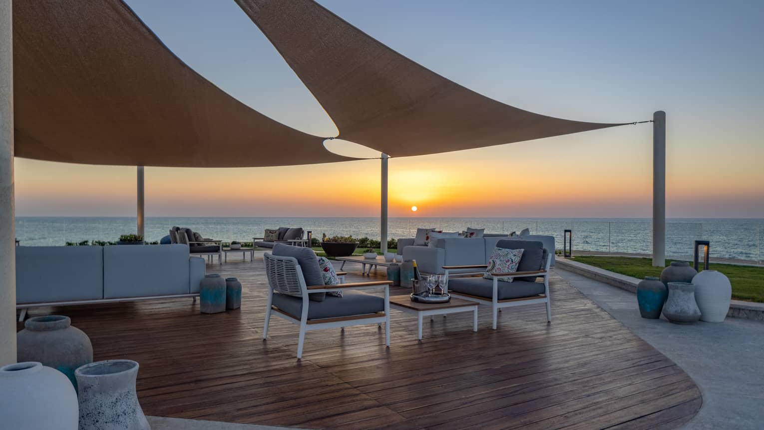 Partially covered patio of The Palace at sunset with lounge chairs and sofa