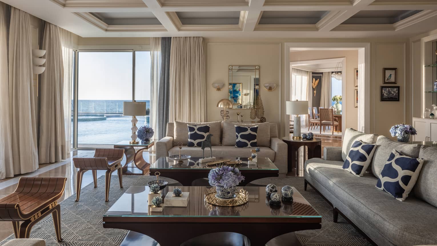 The Palace living area with cream and tan sofas, ergonomic cherry wood coffee tables, sliding glass doors to patio with pool