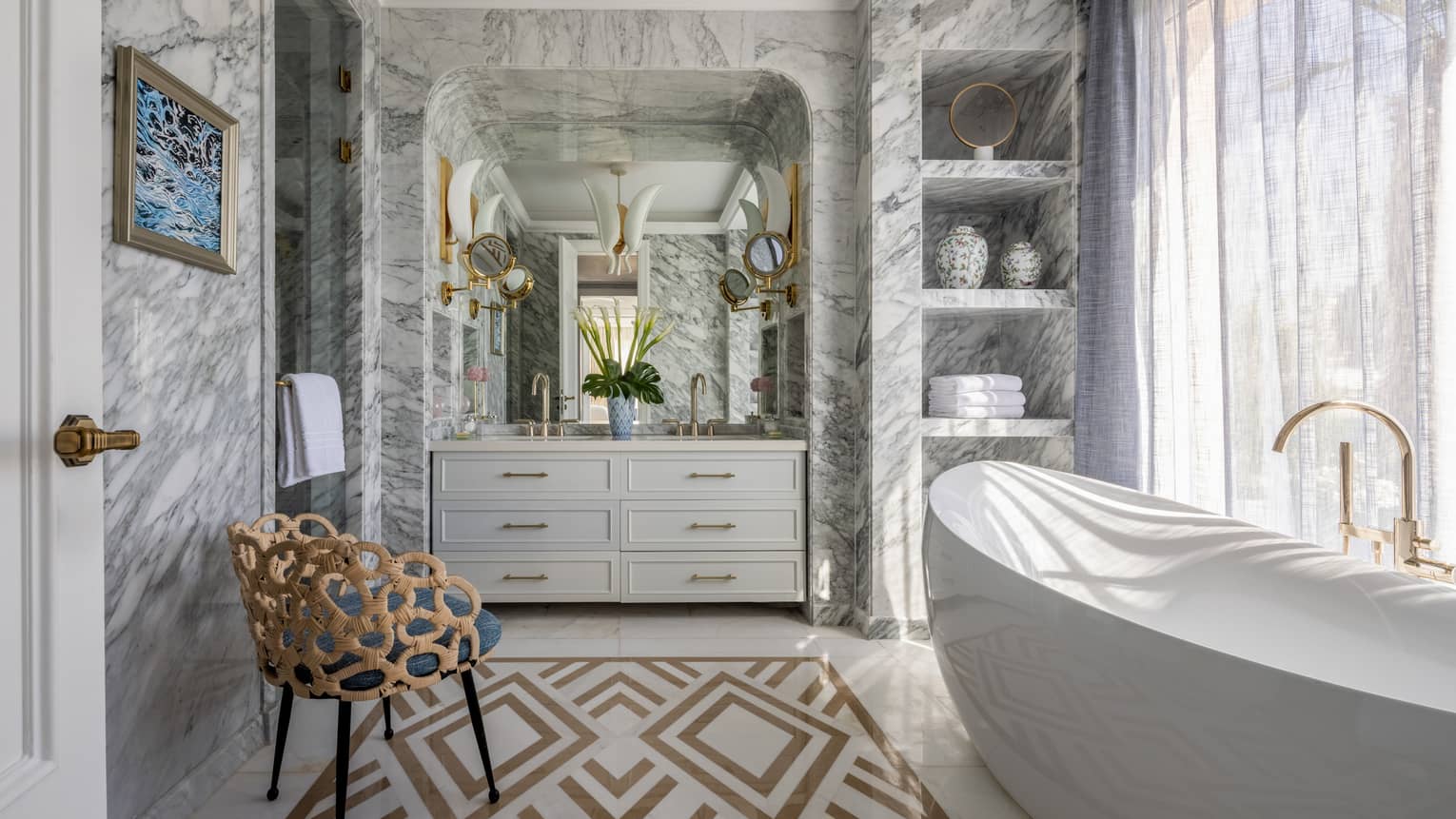 The Palace bathroom with large soaking tub, marble walls, double vanity, built-in shelves