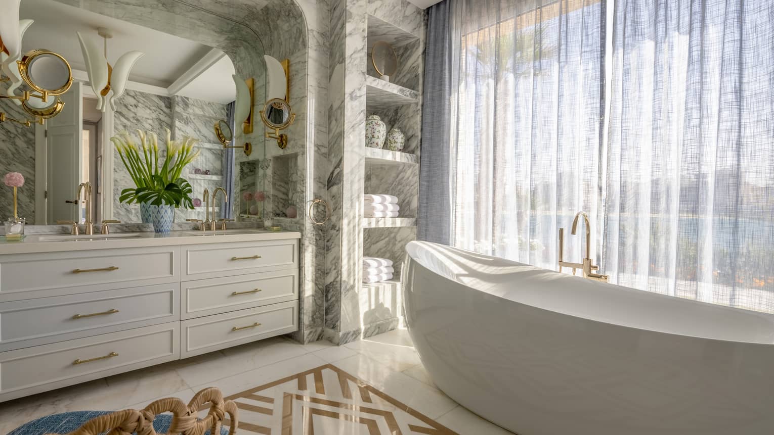 The Palace bathroom with large soaking tub, marble walls, double vanity, built-in shelves