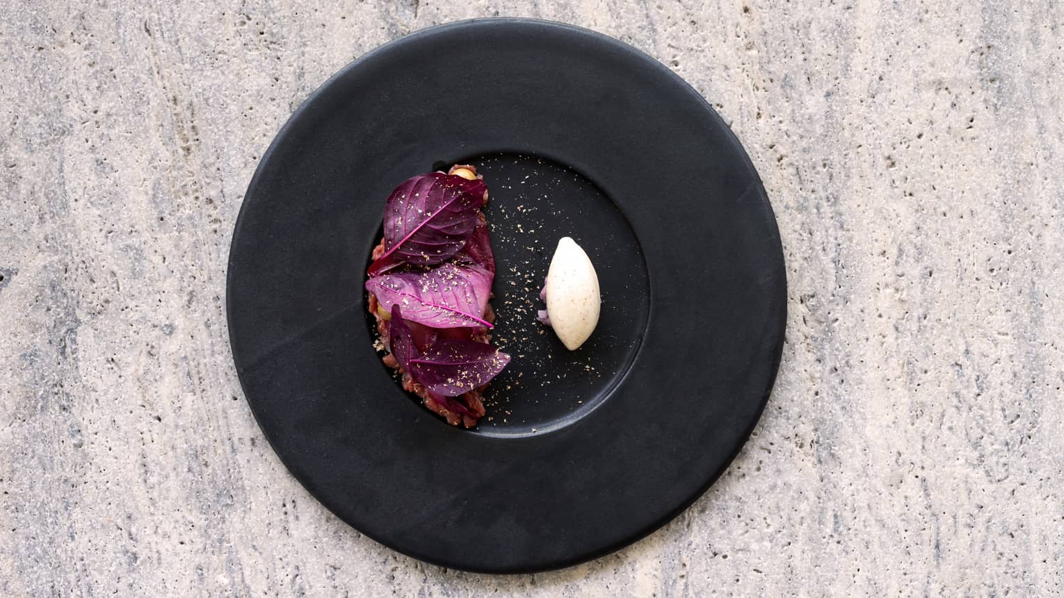 Sheep Tartare with Pickled Red Endives, Rose, Goat Cheese Foam and Nutmeg on black plate