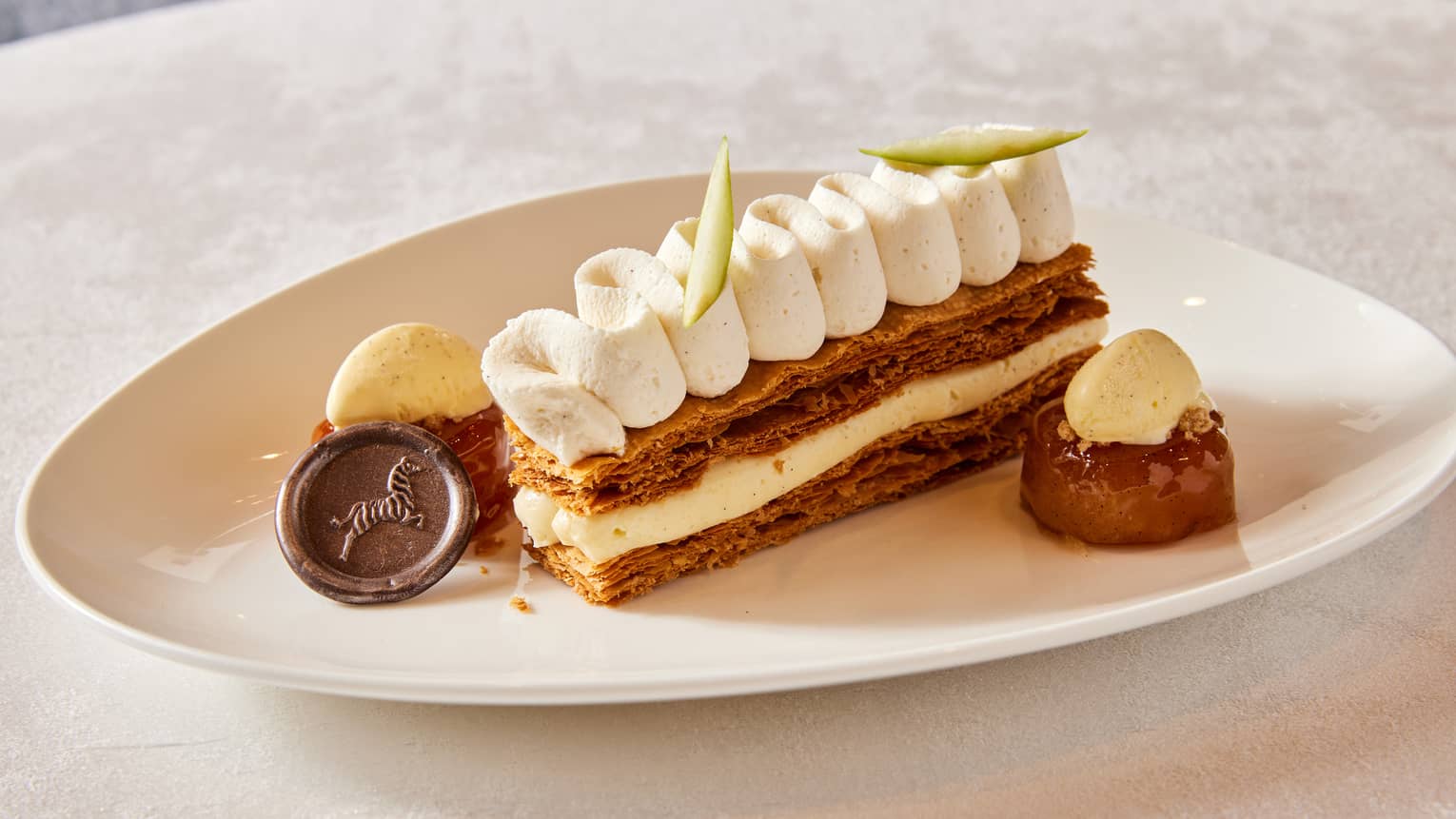 Dessert with icing in the middle and top, with a piece of chocolate on the side.