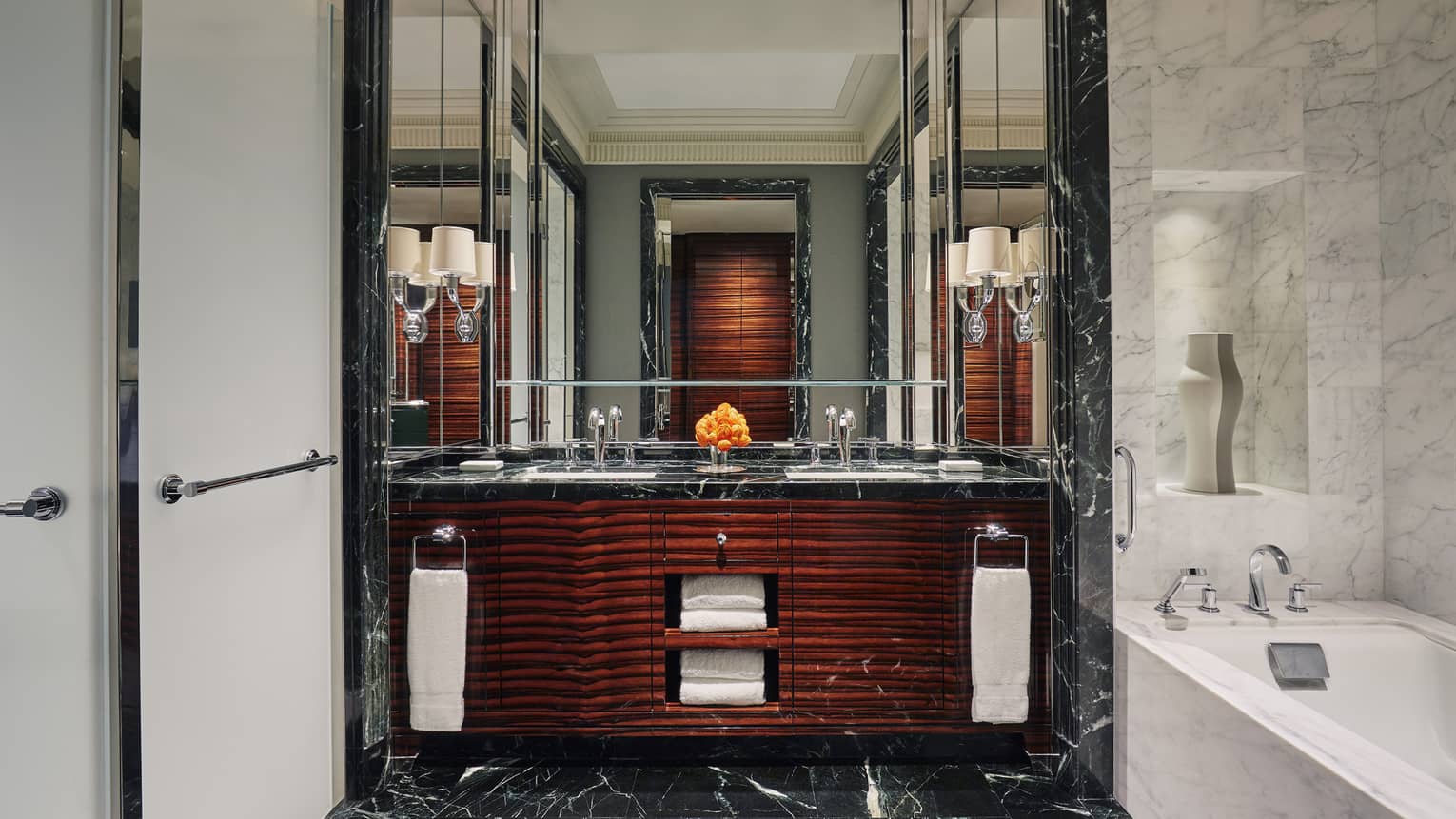 Large bathroom with black marble for the floor can vanity counter, dark wood veneer on the vanity cabinets and a white marble bathtub