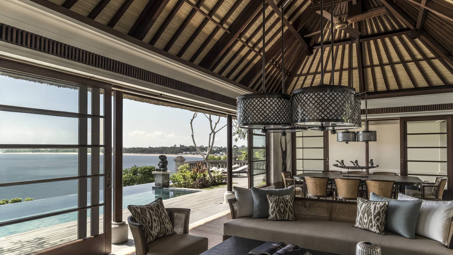 Royal Villa living room with beige sofas, round wicker chandeliers, sliding glass wall to sunny patio