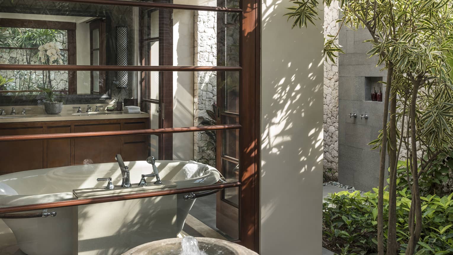 View from outside window looking at freestanding tub inside bathroom, sink