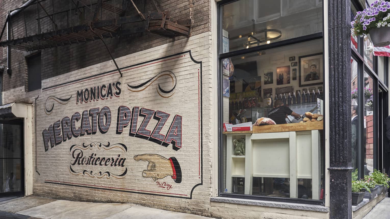white Brick mural on the side of a corner restaurant that reads, "Monica's Mercato Pizza" in Boston's North End