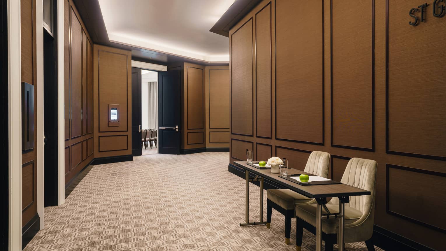St. Germain foyer with two-person table, uplighting, tan carpet, doors leading to meeting rooms 