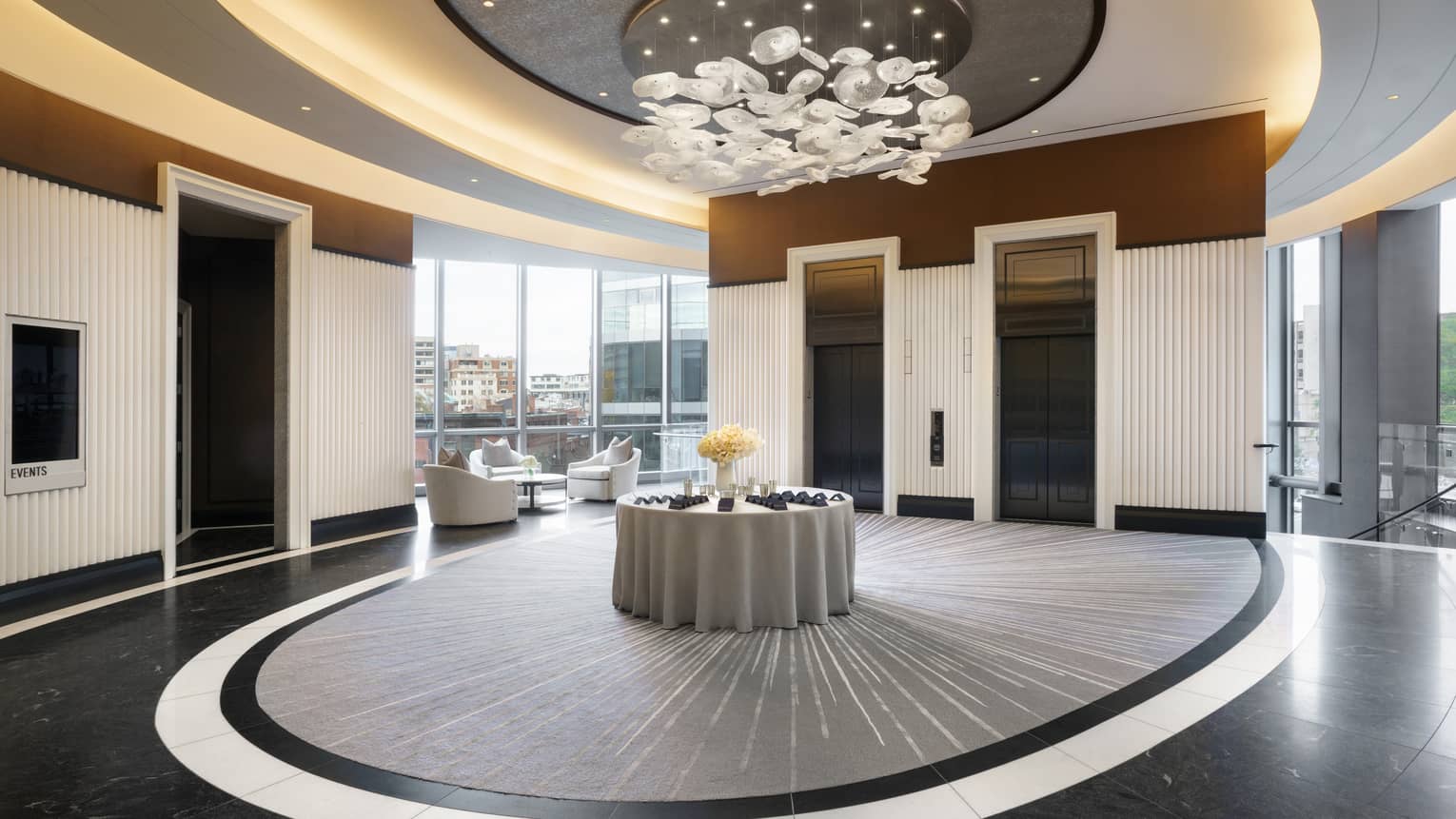 Lobby pre-function area with chandelier, uplighting, two elevators, view of Boston skyline