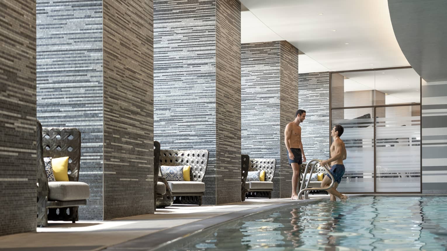 Two men near an indoor pool.