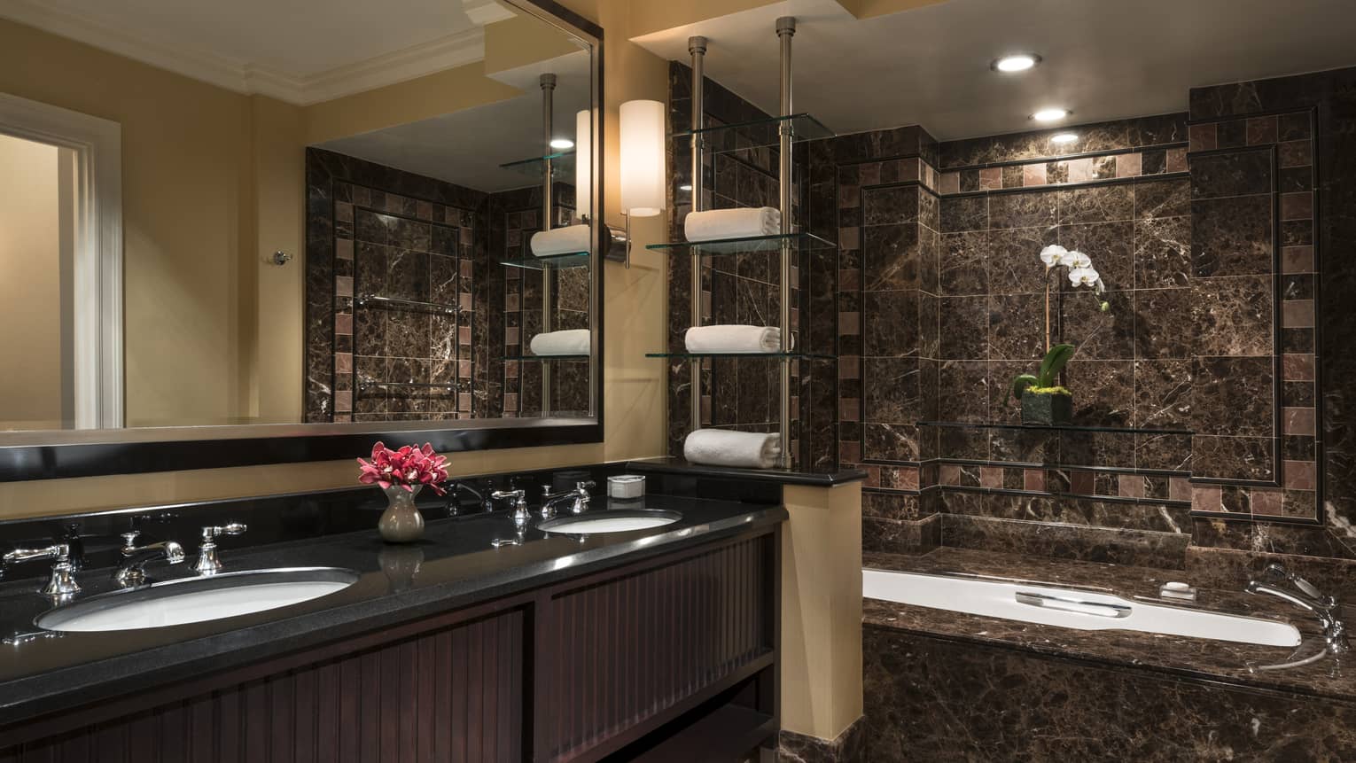 Bathroom with dark brown and tan tiles, tub and double vanity