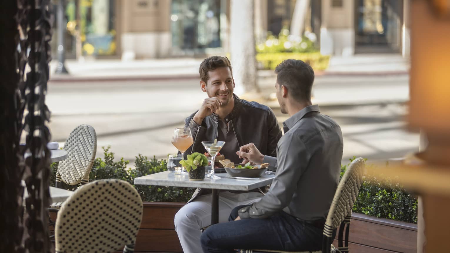 Two men sitting outside eating food.