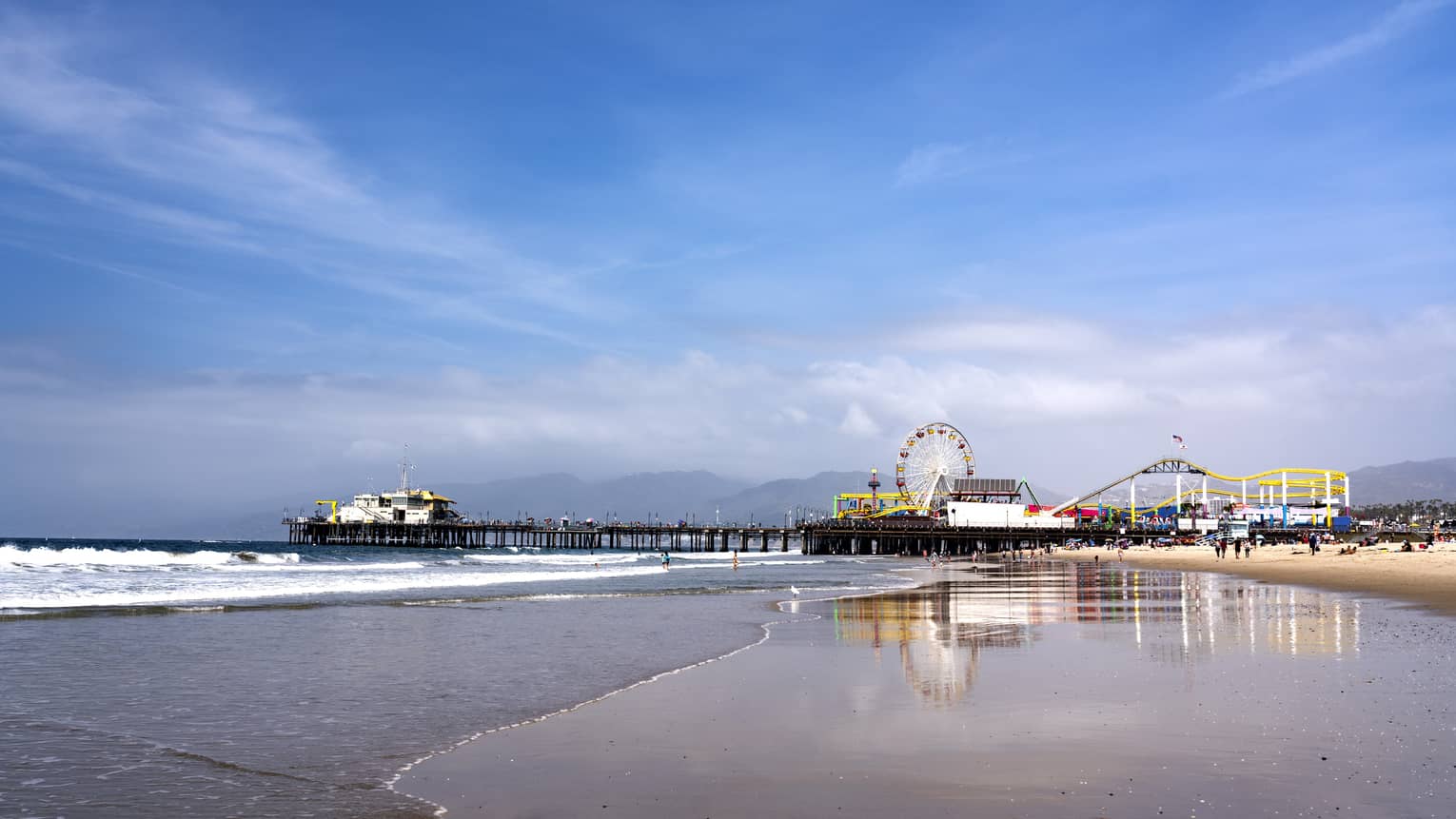 A beach shore with a ferris heel in the distance.