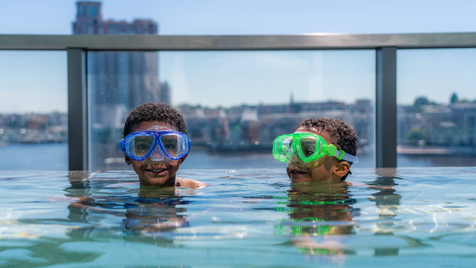 Two young guests wearing goggles and swimming in a rooftop pool
