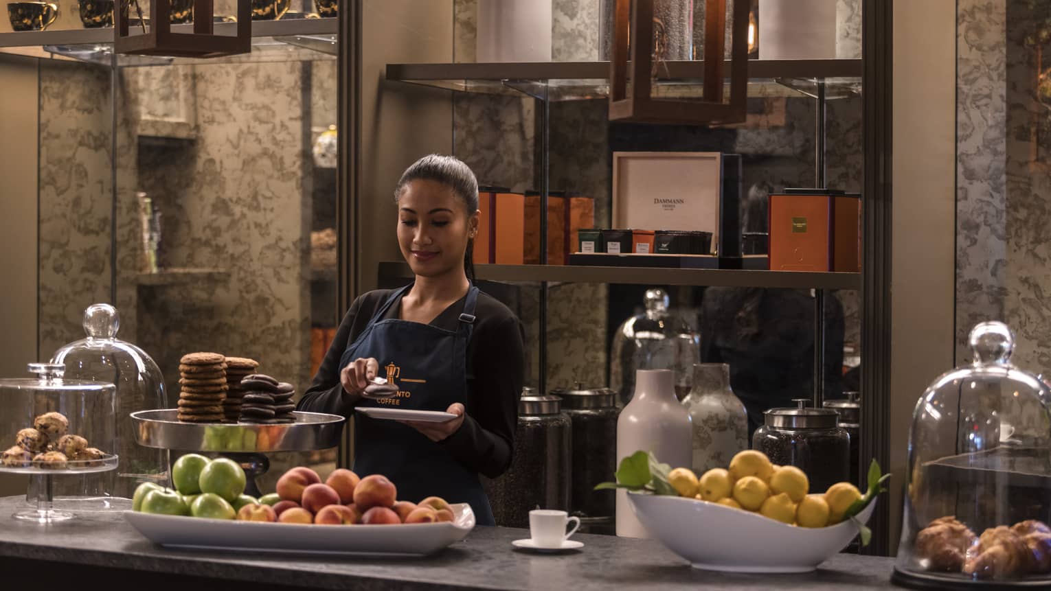 A member of the hotel selecting snacks and fruit to put on a white plate.