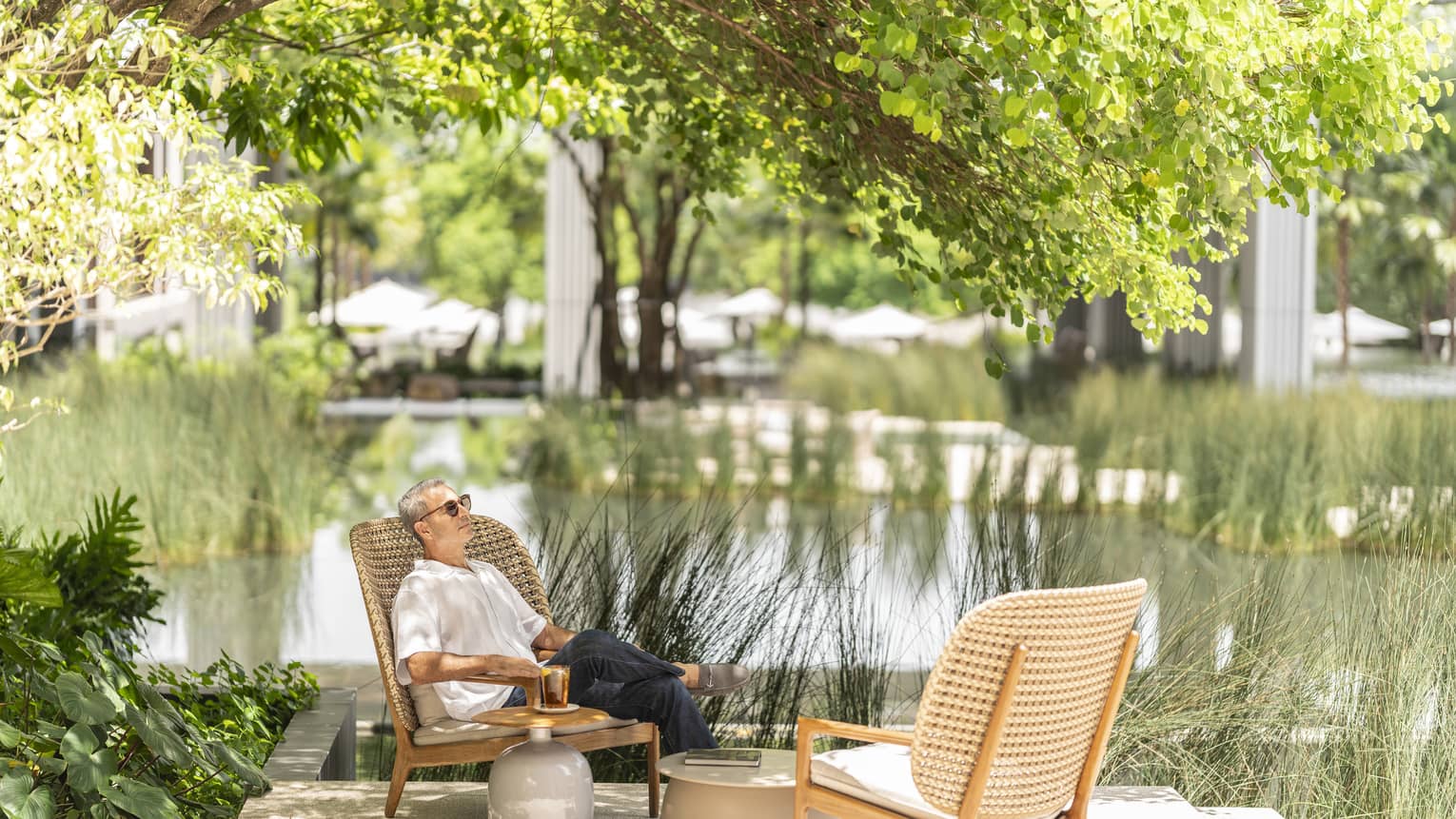Man lounges in rattan chair by the pond in the Central Courtyard