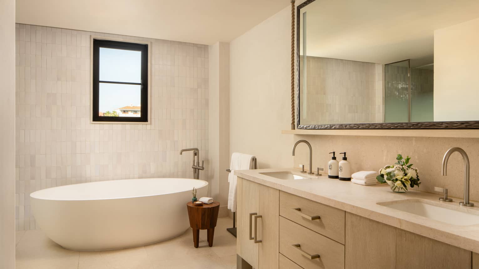 Contemporary bathroom with standalone oval tub, window, and double vanity sinks
