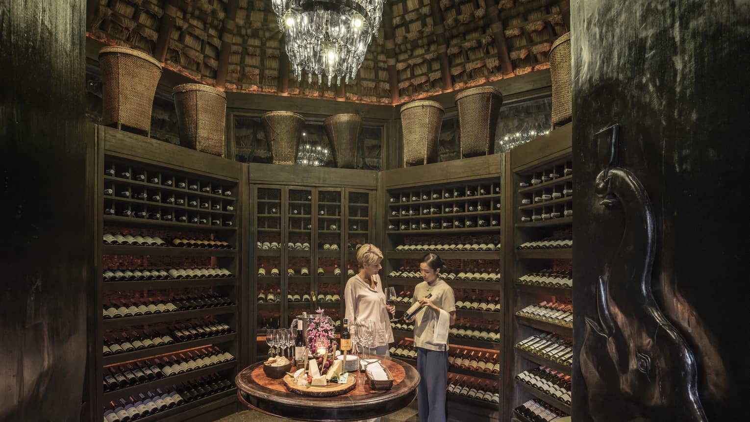 Two people examine wine bottles in Camp Wine Cellar