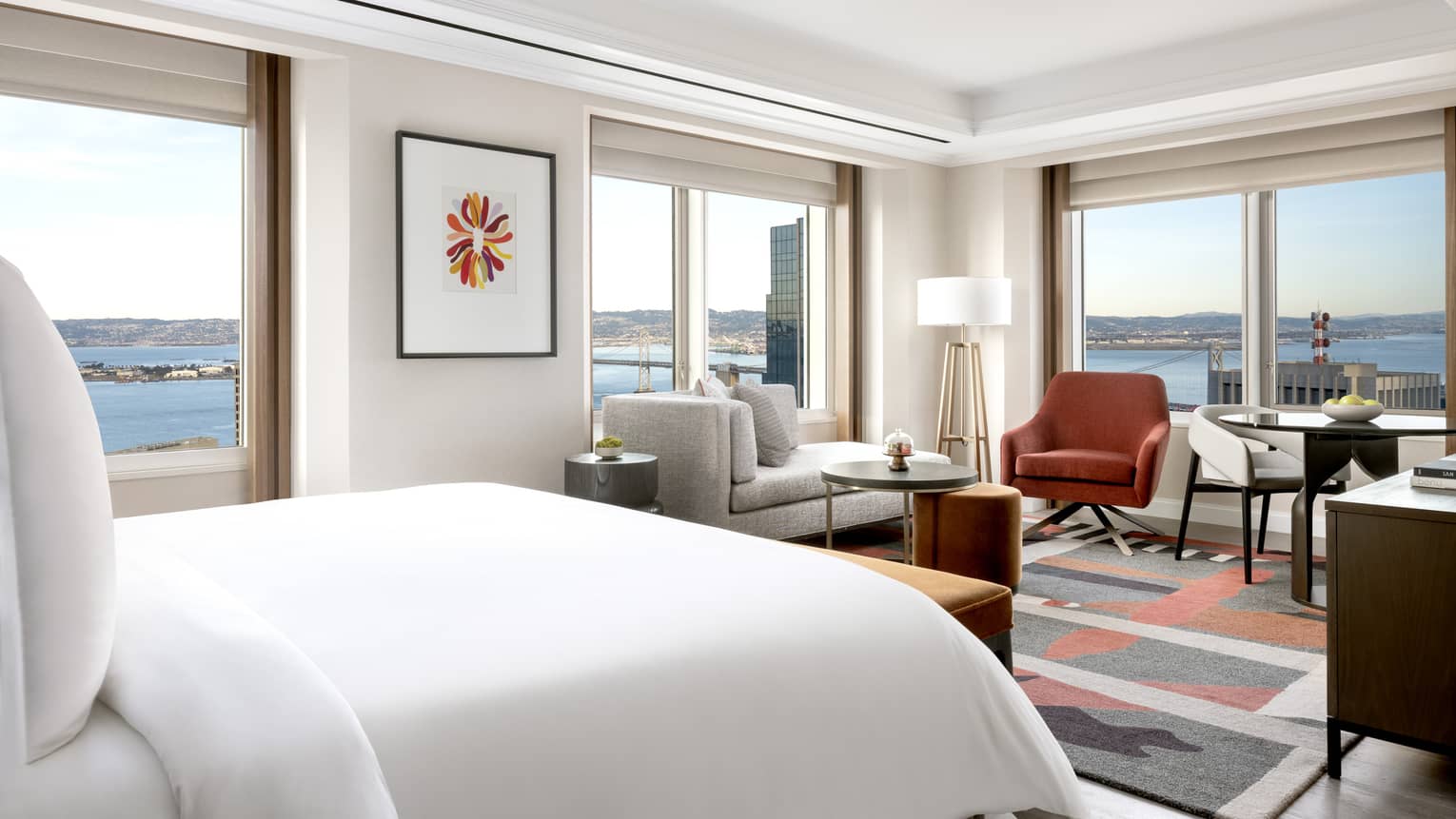 King bed, chaise, and small dining table facing panoramic window