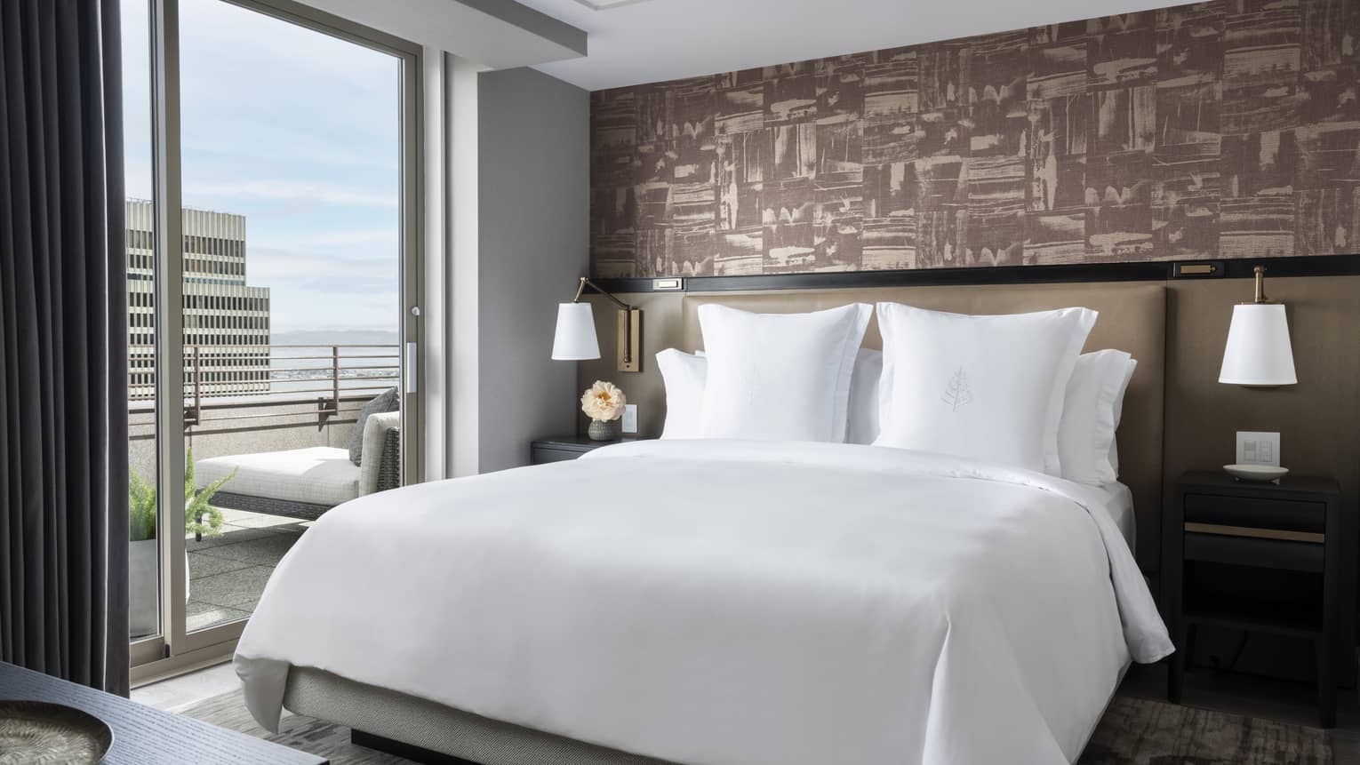 Bedroom with king bed, white sheets, mauve-coloured wallpaper and city-view terrace