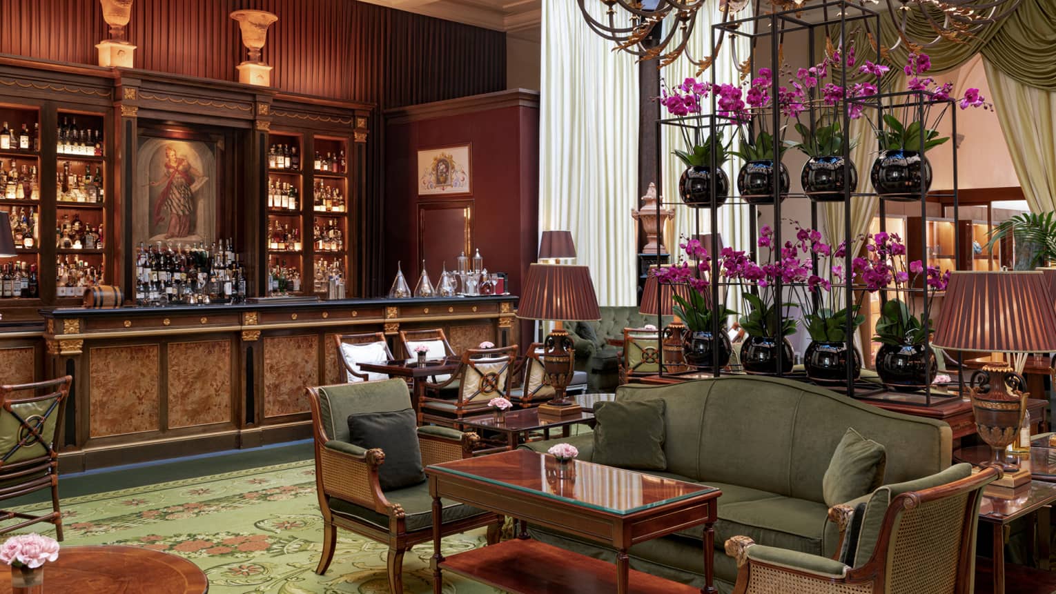 Elegant full mahogany lounge bar in the backdrop of cosy lounge seating in olive tones with purple flower accents