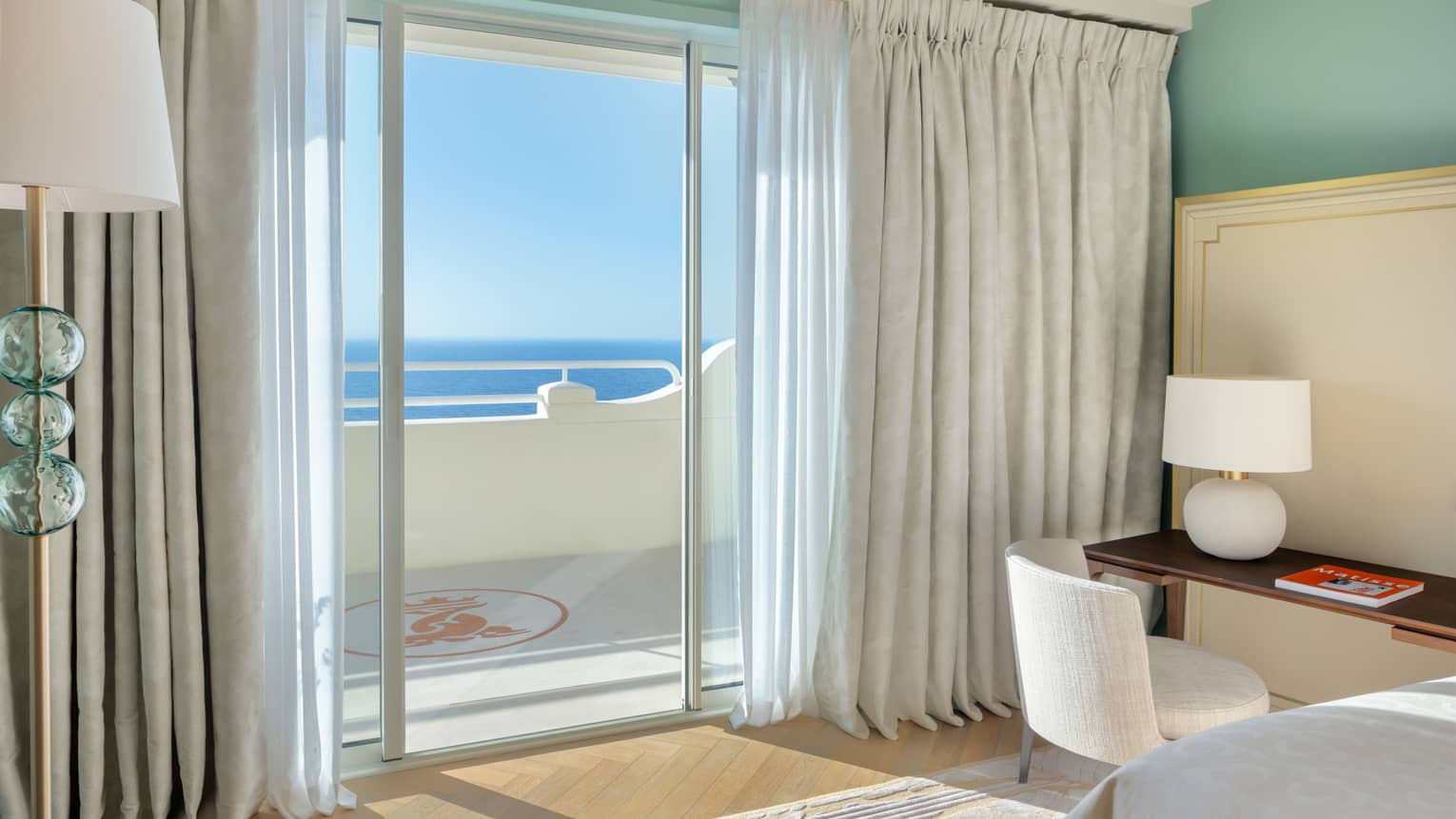 Luxury hotel suite bedroom with desk and walk-out sea-view terrace