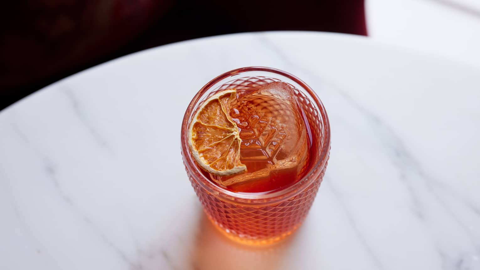 Orange-coloured negroni cocktail in old-fashioned glass and garnished with lime slice