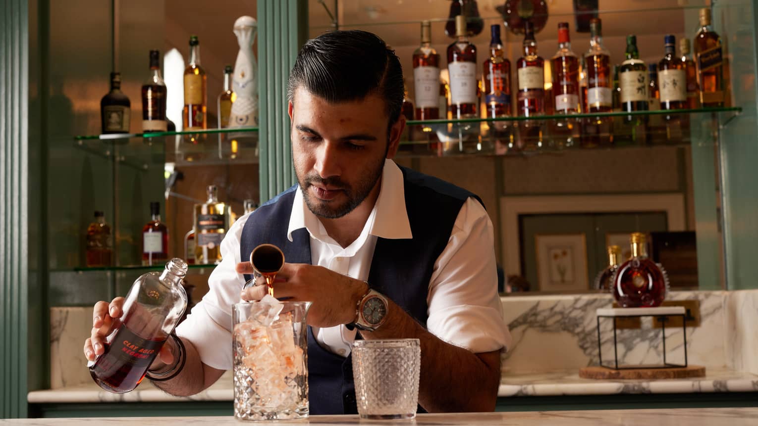 Bartender pouring liquor into a tall crystal pitcher full of ice