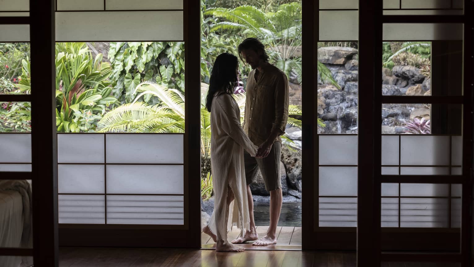 Man and woman stand visible in a garden setting, through frosted doors of a private spa hale